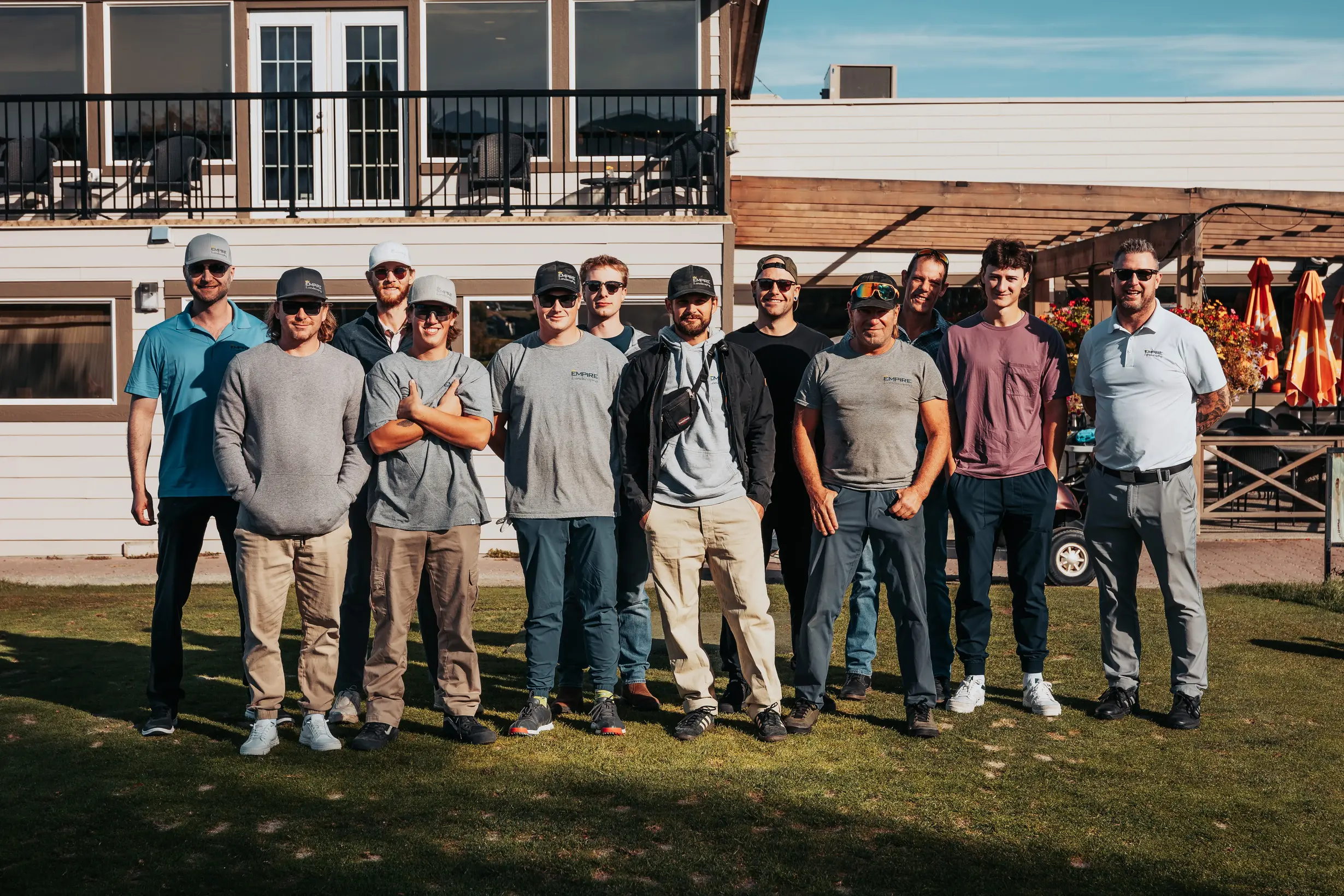 Empire landscaping team posing in-front of a building on golf grass