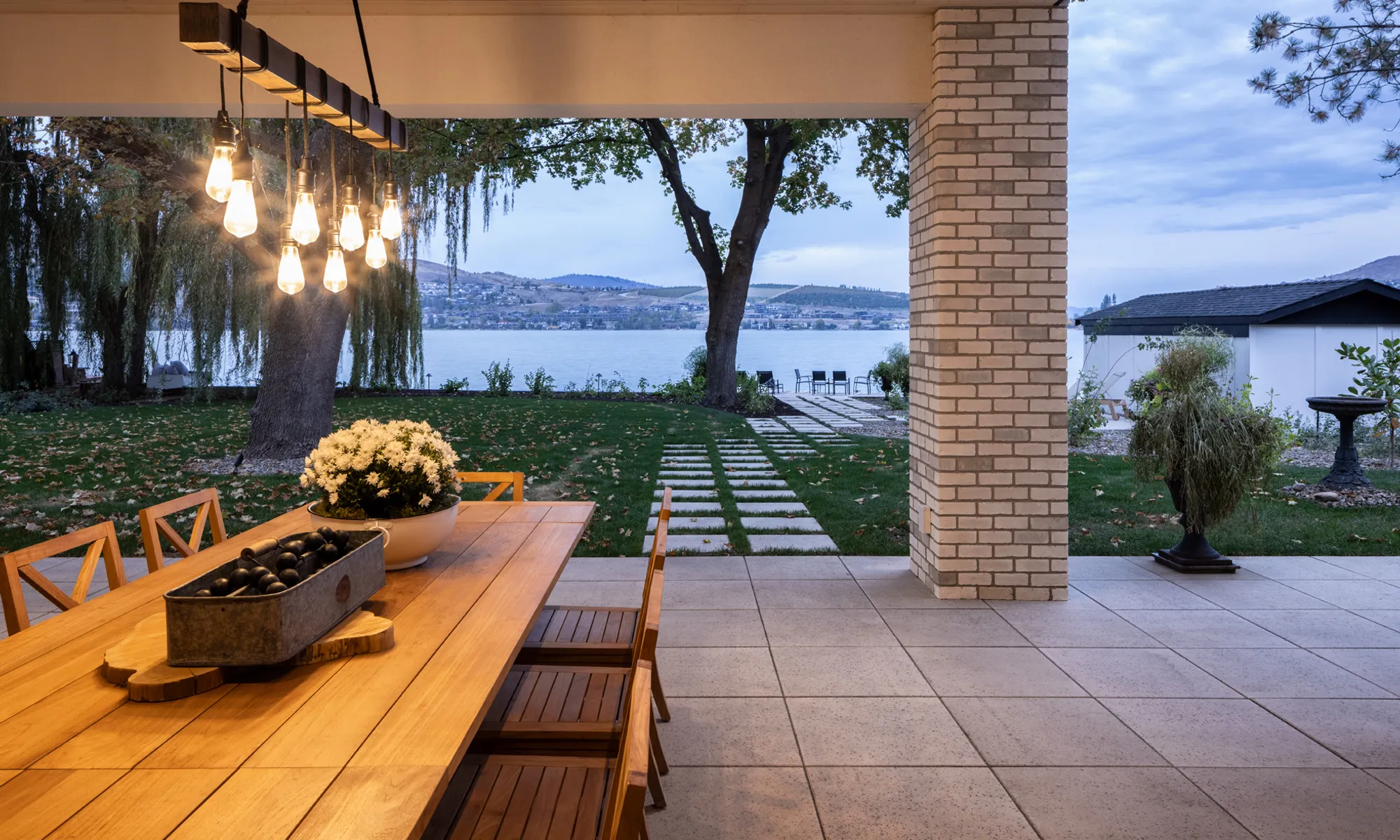 lake front home with pillar and outdoor lighting